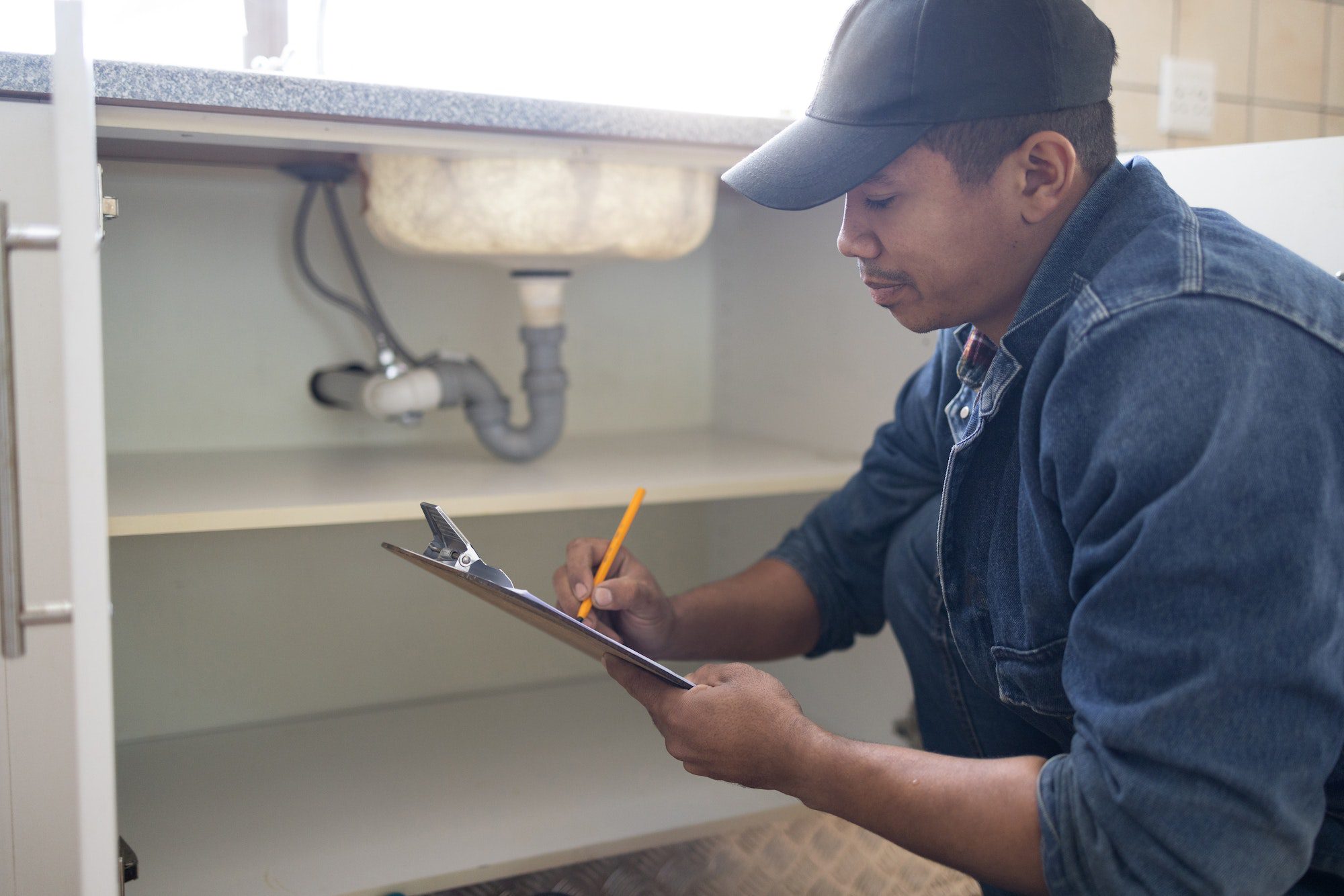 Plumber writing, sink maintenance document and plumbing check of a handyman in a kitchen. Water ins